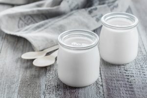Deux pots de yaourt maison avec leurs cuillères sur une serviette