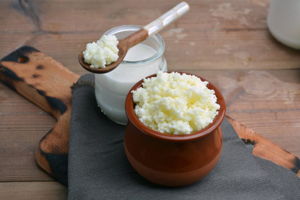 Yaourt et grains de kéfir de lait sur une planche de cuisine