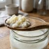 Grains de kéfir de lait dans une cuillère en bois au-dessus d'un bocal